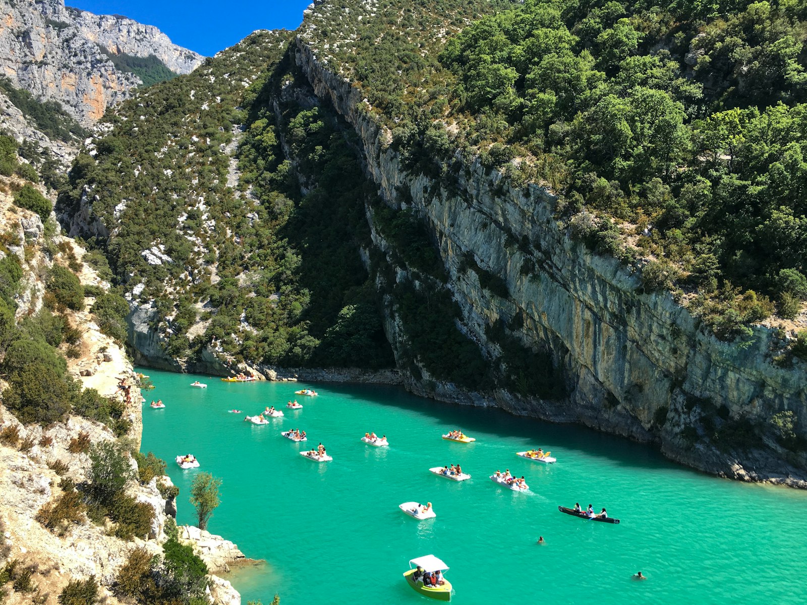 Pedal boats and kayaks on the turquoise water at the mouth of the Verdon Gorge near the Pont du Galetas